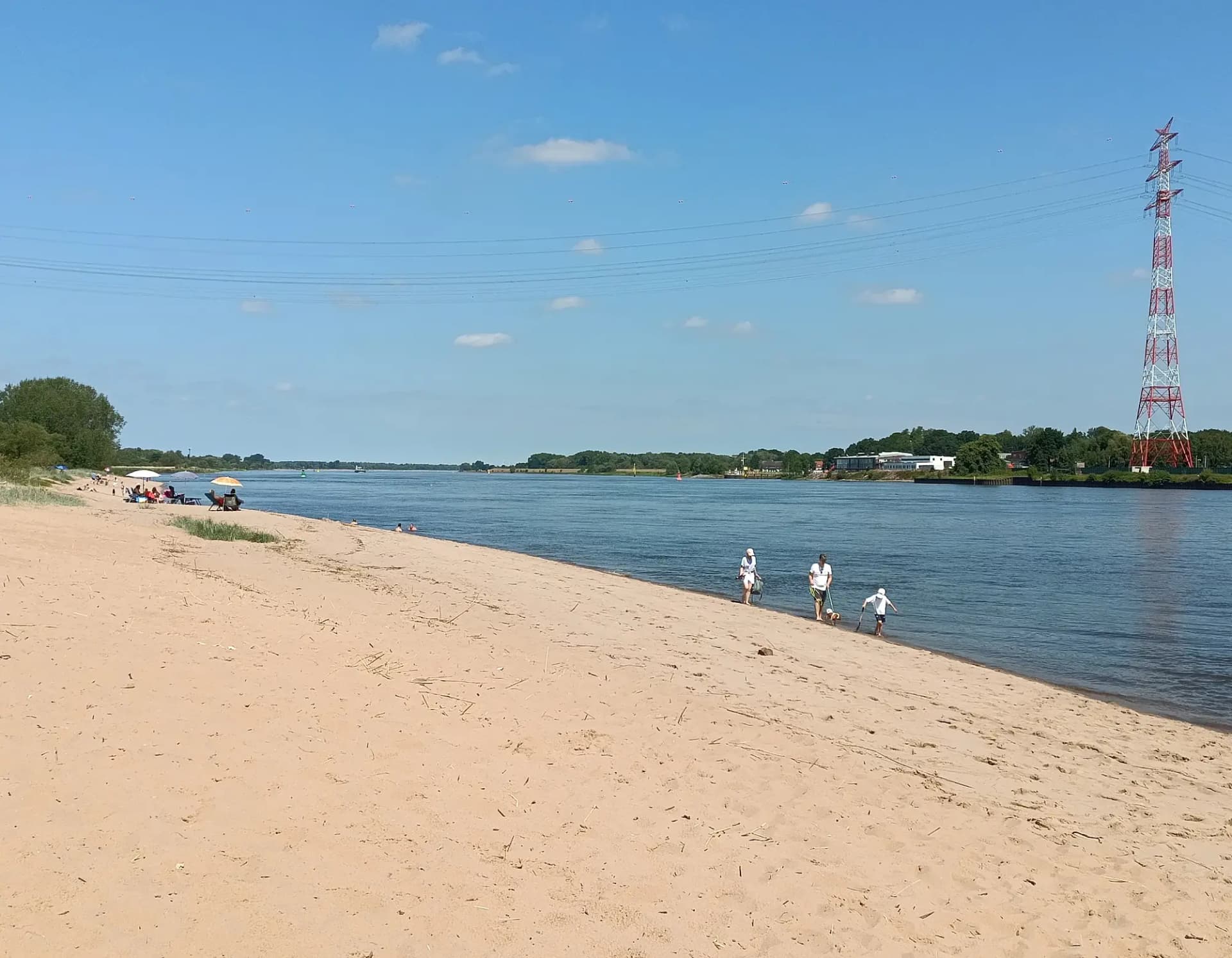 Weser-Sandstrand bei Berne-Juliusplate: heller, breiter Sandstrand, der flach in die Unterweser ausläuft, dahinter das gegenüberliegende Ufer.